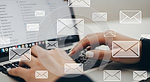 Hands typing on a laptop with email icons floating around