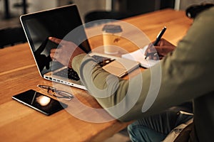 Close-up of hands are typing on a laptop. laptop with notepad and pen on the table, top view