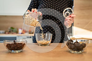 Close up on hands of unknown caucasian woman preparing healthy breakfast oatmeal at home