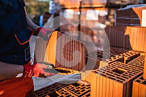 Close up on hands of unknown man construction worker taking hollow clay block ar warehouse or construction site in sunny summer