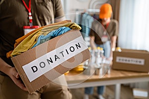 Close up on hands of unknown man volunteer working at the charity foundation holding box with clothes and stuff for donation copy