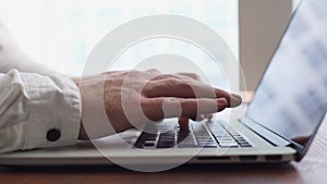 Close-up of hands of unrecognizable businessman typing on laptop computer.