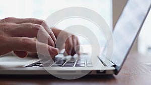 Close-up of hands of unrecognizable businessman typing on laptop computer.