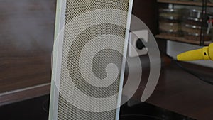 Close-up hands of unrecognizable man cleaning cleaning mesh filter of cooker hood using steam cleaner in modern kitchen