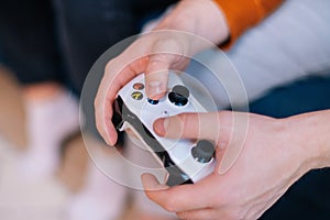Close-up hands of unrecognizable man holding joystick and playing video games on console at home.