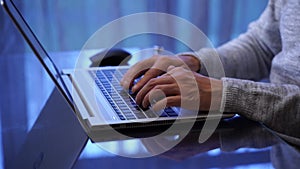 Close-up of hands of unrecognizable man typing on laptop keyboard working home