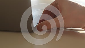 Close-up hands of unrecognizable man unplugging magnetic USB-C power cord from laptop on table. Close up of man removing