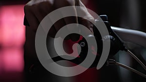 Close-up hands of unrecognizable mechanic insisting speed switches on mountain bicycle handlebar in dark garage of