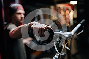 Close-up hands of unrecognizable mechanic insisting speed switches on mountain bike handlebar working in bicycle repair