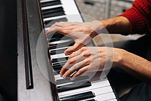 Close-up hands of unrecognizable musician man playing on digital electronic piano synthesize at home.