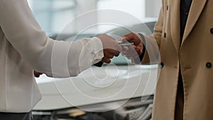 Close up hands unrecognizable seller and buyer african american woman dealer give automobile keys to man customer buying