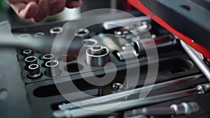 Close-up hands of unrecognizable worker man opening toolbox with auto car tools taking and connecting head socket with