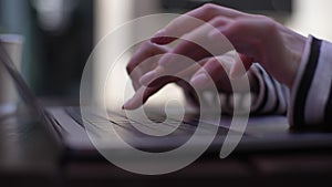 Close-up hands of unrecognizable young woman working on laptop typing sitting at table in outdoor cafe in summer day