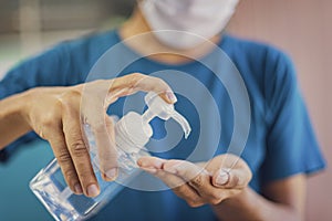 Close up of hands using antiseptic gel, alcohol gel to disinfect hands over a work desk in at home. Preventive measures during the photo