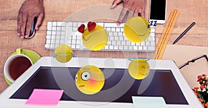 Close-up of hands using computer with emojis at desk
