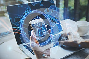 Close up of hands using laptop and smartphone with abstract glowing blue dollar sign and map with charts on blurry background.