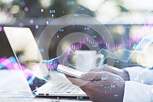 Close up of hands using laptop and smartphone with abstract glowing candlestick forex chart with index and grid on blurry desktop