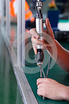 Close-up of hands using pneumatic screwdriver