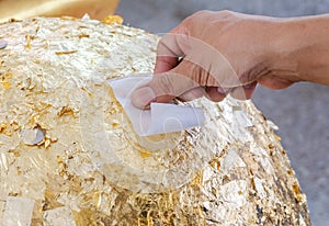 Close up Hands were gilded,Cover statue of Buddha with gold leaf