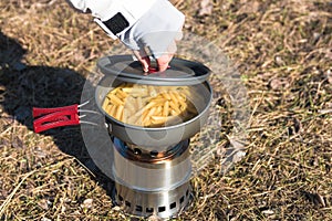 Close up hands of woman cooking pasta on wood burner in wild camping