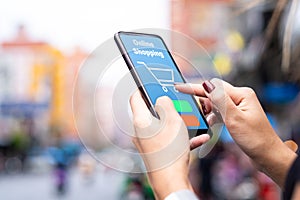 Close-up of hands of a woman shopping online in the city street . Modern lifestyle .