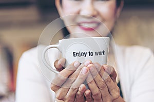 Close up hands of woman sitting office desk holding sweet coffee cup relax and enjoy with happy time. Hot coffee mug in hand.