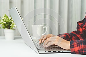 Close up. hands woman typing keyboard on laptop at house. Student searching data for research, and learning online in office