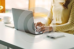 Close up hands of woman using computer calculating household finances or taxes