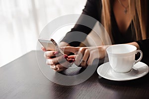 Close up of hands woman using her cell phone in restaurant, cafe.