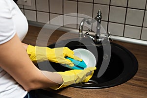 Close up hands of Woman Washing Dishes in the kitchen. Hands with sponge wash the plate under running water