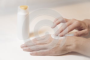 Close up of the hands of a woman who takes care of herself by rubbing cream with two fingers on the back of her left hand photo