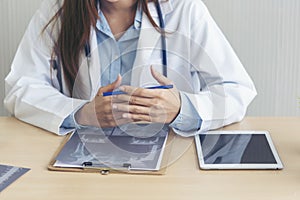 Close up hands of women doctor using laptop, tablet working medical clinic looking CAT scan xray film. women doctor write