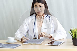 Close up hands of women doctor using laptop, tablet working medical clinic looking CAT scan xray film. women doctor write