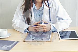 Close up hands of women doctor using laptop, tablet working medical clinic looking CAT scan xray film. women doctor write
