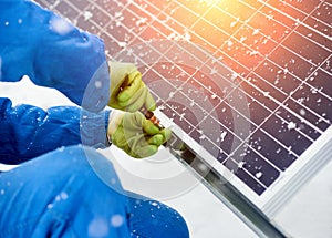 Close-up of hands worker installing solar panels in snowy weather
