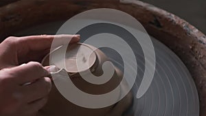 Close up of hands working clay on potter`s wheel. Potter shapes the clay product with pottery tool. Handmade Background