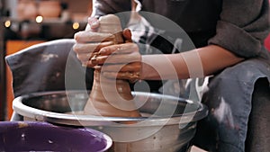Close up of hands working clay on potter's wheel. Potter shapes the clay product with pottery tools on the