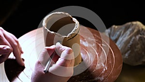 Close up of hands working clay on potter`s wheel. Potter shapes the clay product with pottery tools on the potter`s