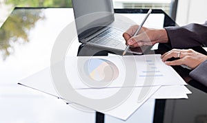 Close up hands writing of young and smart business woman manager who is working on data analysis and computer laptop on working