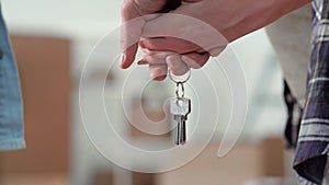 Close-up hands of young couple holding keys to a new apartment