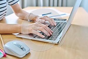 Close up of hands of young female student typing on laptop