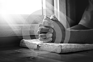 Close up hands of young man praying and reading holy bible, christian black white concept