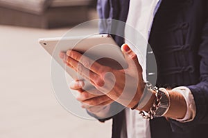 Close up hands of young man using tablet on street