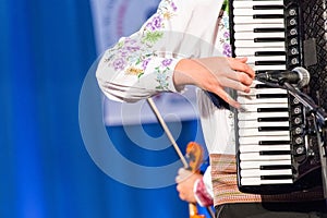 Close up of hands of young Romanian man perform a folk music on Accordion in traditional folkloric costume. Folklore of Romania