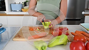 Close up hands of young sporty woman cutting and cooking fresh natural vegetables at kitchen and cooking for healthy lunch.