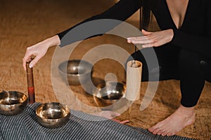 Close-up of the hands of a young woman transmitting a message with the help of singing bowls and a koshi bell to another