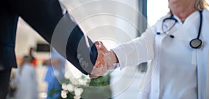 Close-up of handshake of doctor and business woman.