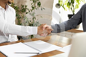 Close-up handshake of two men, office workers, colleagues making deal in business office. Concept of coworking, business