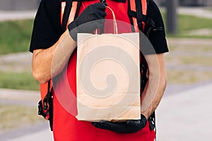 Close up handsome courier man holding paper bag with food at street outdoors worker grocery to house door to door