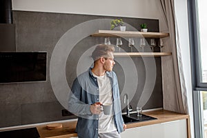 Close up of a handsome man drinking tea in the kitchen in the morning